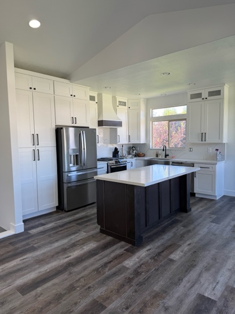 The finished white shaker kitchen with a dark island and Calacatta quartz countertops