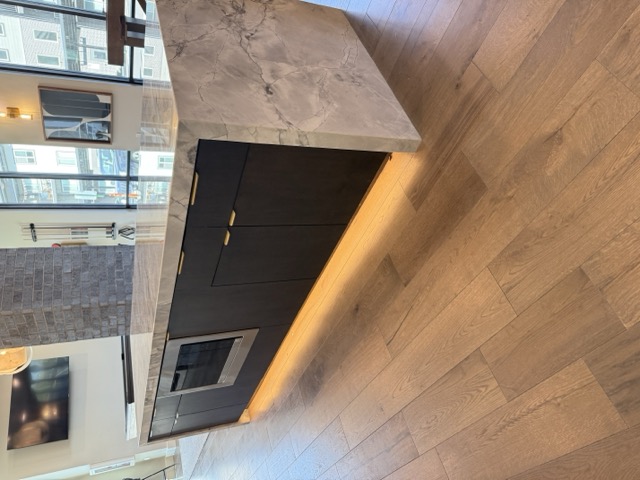 Dark cabinet island with marble waterfall countertop and LED under-lighting