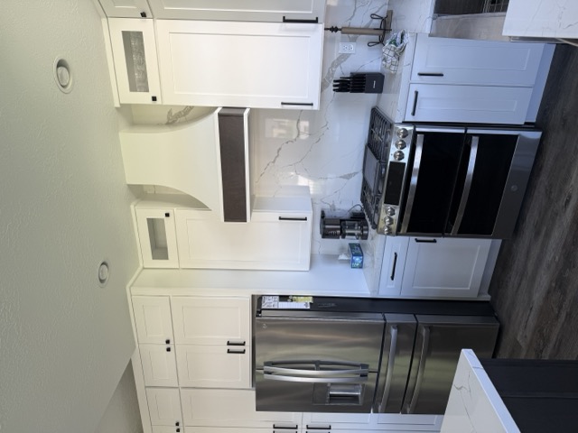 White shaker cabinets with custom range hood and quartz backsplash