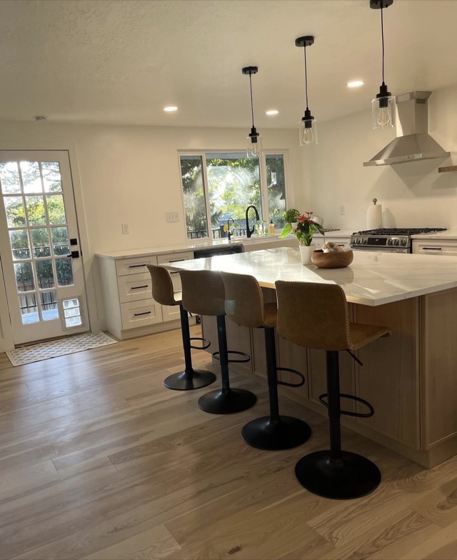 Kitchen island with bar seating, pendant lights, and stainless range hood