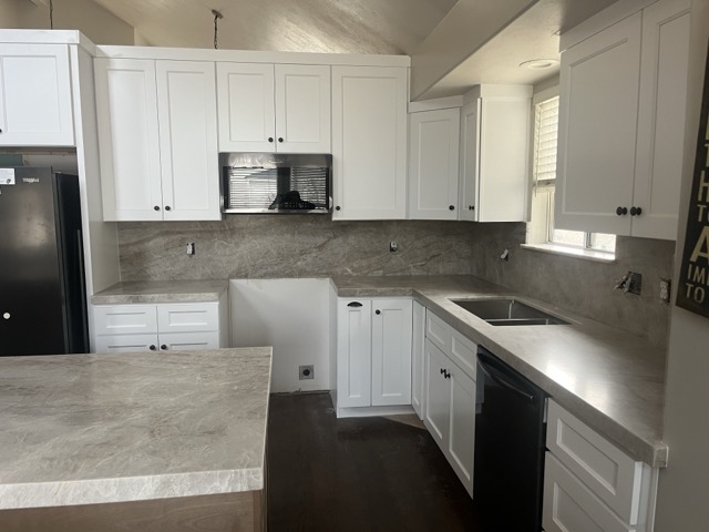 White shaker cabinets with gray stone countertops and vaulted ceiling