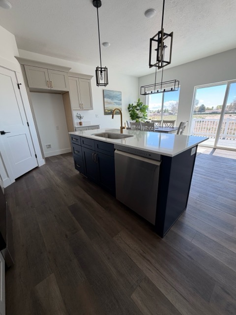 Navy blue shaker island with a white quartz top and brass gooseneck faucet, set against greige perimeter cabinetry
