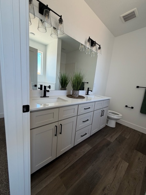 Light greige shaker double vanity with speckled quartz countertop, twin frameless mirrors and black Edison vanity lights