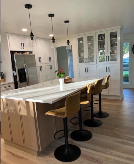 White-oak kitchen island with a thick white quartz top and camel leather counter stools