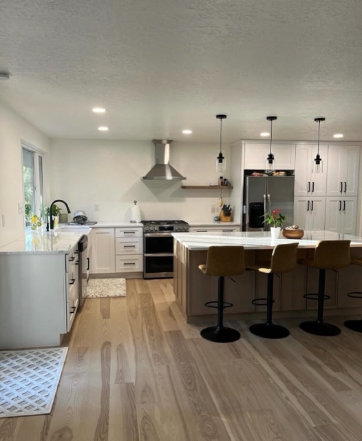 Open-concept kitchen with white shaker perimeter cabinets, a large white-oak island and pale wide-plank floors
