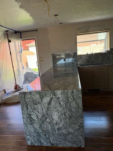Kitchen remodel in progress with the new grey-green granite waterfall peninsula set over dark hardwood flooring