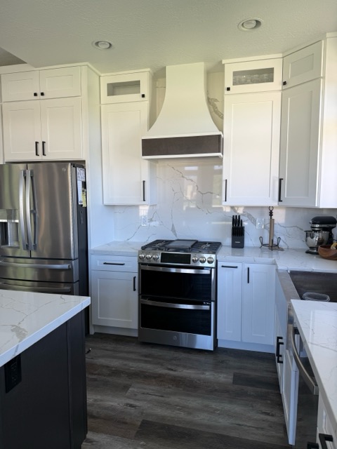 White shaker range wall with a plaster hood, stainless double-oven range and Calacatta quartz counters