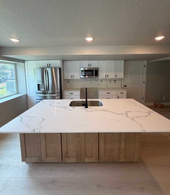 Modern white shaker kitchen with a natural maple island, white quartz waterfall countertop and matte black gooseneck faucet