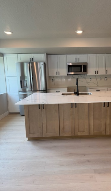 White shaker kitchen with a maple island, Calacatta-look quartz waterfall counter and full-height quartz backsplash